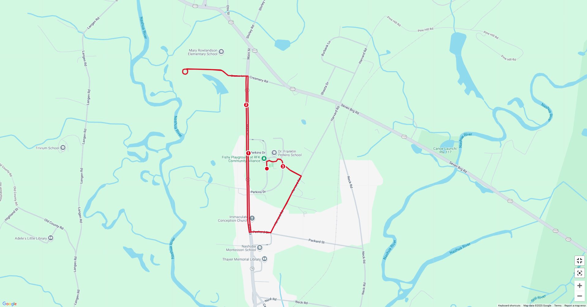 A digital map displaying a race or event route outlined in red. The route runs through various landmarks, including the Fishy Playground at RFK Community Alliance, Dr. Franklin Perkins School, and Immaculate Conception Church. The map also highlights natural features such as the Nashua River and surrounding forested areas. The route follows a combination of roads and pathways, weaving through a mix of urban and natural landscapes.